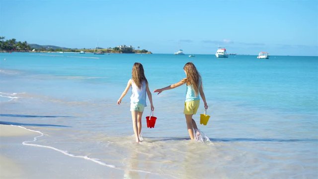 Adorable little girls playing with sand on the beach.