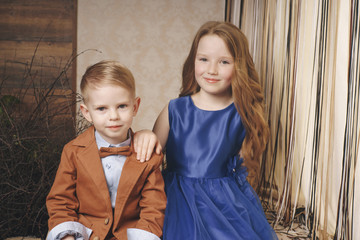 Two preschool children boy and girl sit together at the outdoor in the city in relation