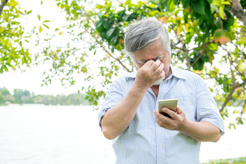 Senior man trying to use a mobile device. Very confuse old chinese man trying very hard to use his...