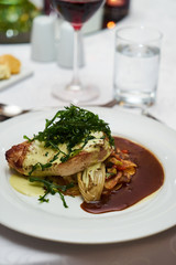 People eating roasted organic chicken dish with tarragon, mustard sauce, rosemary, potatoes tian and confit fennel, close-up. Delicious healthy food dinner on serving table concept