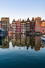 Blick auf die bunten Fassaden typischer Amsterdamer Häuser, die sich während des Sonnenuntergangs im Amstel-Kanal in Amsterdam spiegeln