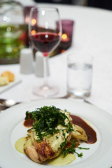 People eating roasted organic chicken dish with tarragon, mustard sauce, rosemary, potatoes tian and confit fennel, close-up. Delicious healthy food dinner on serving table concept