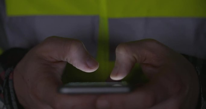 Building Contractor In Yellow Hi Vis PPE Typing Message Late At Night At Work, Front View, Symmetrical, 4k Slow Motion, Negative Space For Graphics.