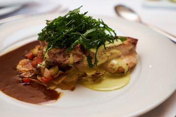 People eating roasted organic chicken dish with tarragon, mustard sauce, rosemary, potatoes tian and confit fennel, close-up. Delicious healthy food dinner on serving table concept