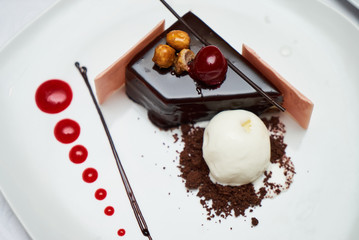 Black forest Cake with cherry, vanilla ice-cream, chocolate and cup of hot tea on table. Delicious sweet dessert breakfast on table background, close-up