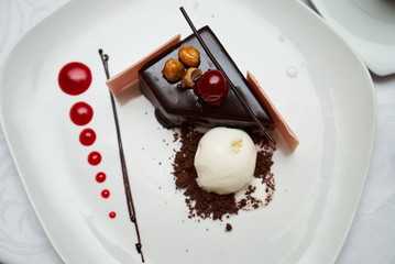 Black forest Cake with cherry, vanilla ice-cream, chocolate and cup of hot tea on table. Delicious sweet dessert breakfast on table background, close-up