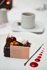 Black forest Cake with cherry, vanilla ice-cream, chocolate and cup of hot tea on table. Delicious sweet dessert breakfast on table background, close-up