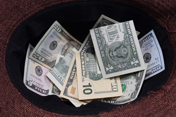 money in hats, passersby give dollars for music in a hat