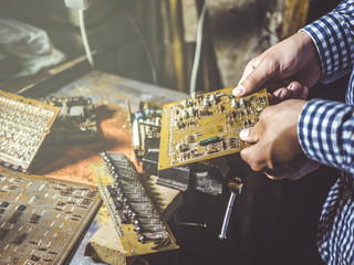 close up hand repairing board circuit chip in workshop