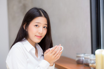 Beautiful  young asian woman drinking coffee and smile in the morning at cafe, girl sitting in coffee shop for breakfast and leisure during free time.