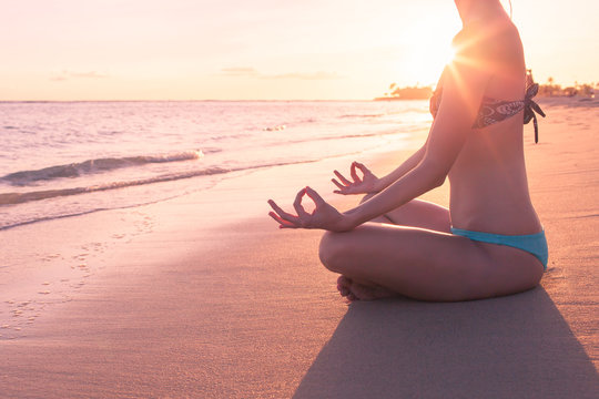 Female sitting on the beach meditating. Meditation, and relaxation concept. 
