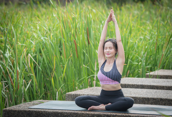 Beautiful woman practicing yoga in the park.
