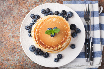 Delicious pancakes close up, with fresh blueberries on rusty background. Top view with copy space