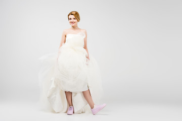Fototapeta na wymiar bride in white wedding dress and pink sneakers, isolated on grey, feminism concept