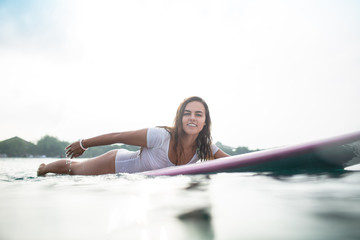 sporty young woman swimming on surfboard in ocean