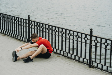 Handsome caucasian male stretching before running in the morning around the lake.