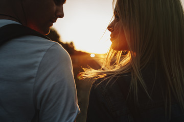Stunning close up portrait of a amazing couple looking to each other smiling against sunset in...