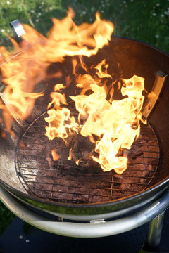 Open fire in the grill to grill a sausage with a charcoal barbecue in the garden
