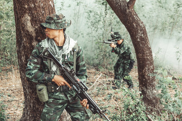 Soldier standing behind a tree ready to attack. Chinese male soldier standing behind a large tree...