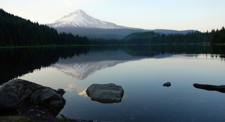 Mount Hood is shrouded in mist and reflected in the still water of Trillium Lake as the sun rises