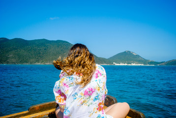 Back view of the young woman relaxing on the boat and looking to the sea. Arraial do Cabo, Brazil