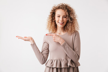 Smiling blonde curly woman in dress holding copyspace on palm