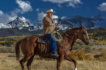 Cowboy rides horse across historic Last Dollar Ranch on Hastings Mesa, SW Colorado, San Juan Mountains