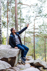 guy sits in the woods on a rock