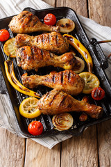 Delicious food: grilled chicken drumstick legs with vegetables in a grill pan close-up on a table. vertical, rustic