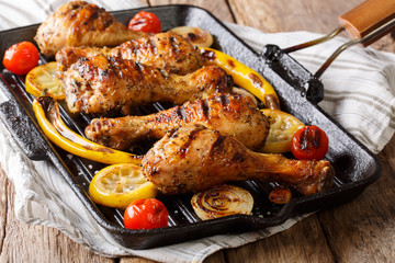 Home barbecue grilled chicken drumstick legs with vegetables in a frying pan grill closeup. horizontal