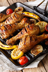 Fried chicken drumstick with vegetables in a grill pan close-up. vertical