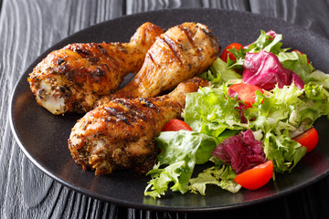Grilled chicken drumsticks and vegetables on black background closeup. horizontal
