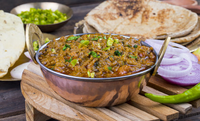 Indian Cuisine Sev Tamatar Also Called Sev Tamaeta or Sev Tameta is Served With Chapati, Papad, Onion or Raita. It is Made With Tomato And Onion Gravy With a Twist of Spicy Sev on Wooden Table
