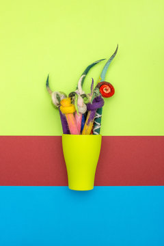 Pencils in a cover of fulled wool in a green cup on a colored background