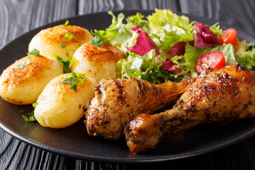 Spicy grilled chicken drumstick with potatoes and fresh salad close-up. horizontal