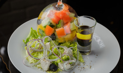 Greek salad with sauce and spices on a glass background