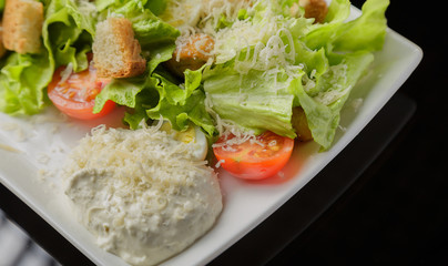 Caesar salad on a white plate and a glass background