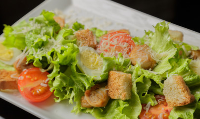 Caesar salad on a white plate and a glass background
