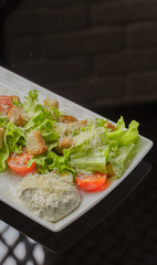 Caesar salad on a white plate and a glass background