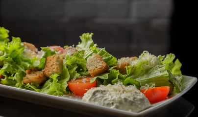 Caesar salad on a white plate and a glass background