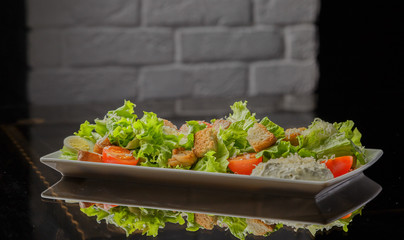 Caesar salad on a white plate and a glass background