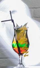 Glass with a cocktail on a glass table and a brick background
