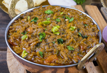 Indian Cuisine Sev Tamatar Also Called Sev Tamaeta or Sev Tameta is Served With Chapati, Papad, Onion or Raita. It is Made With Tomato And Onion Gravy With a Twist of Spicy Sev on Wooden Table