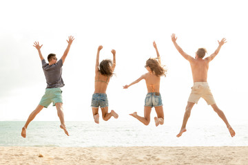 Happy energetic group of friends jumping at the beach during summer holidays