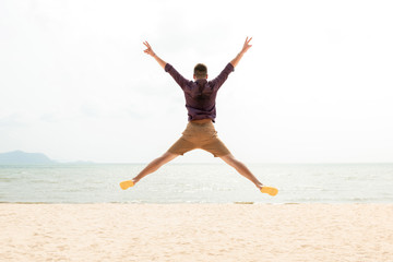 Excited energetic happy man jumping at the beach