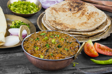 Indian Cuisine Sev Tamatar Also Called Sev Tamaeta or Sev Tameta is Served With Chapati, Papad, Onion or Raita. It is Made With Tomato And Onion Gravy With a Twist of Spicy Sev on Wooden Table