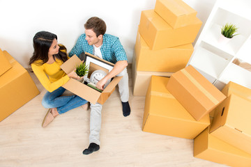 Couple sitting on the floor unpacking box after moving into new house