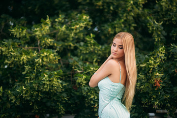 Blonde girl in turquoise color dress posing to the photographer