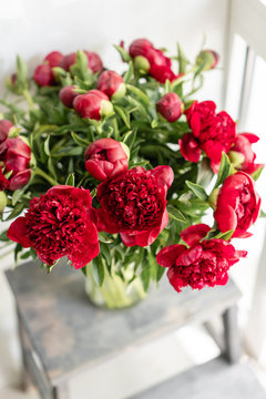 Lovely flowers in glass vase. Beautiful bouquet of red peonies . Floral composition, scene, daylight. Wallpaper. Vertical photo