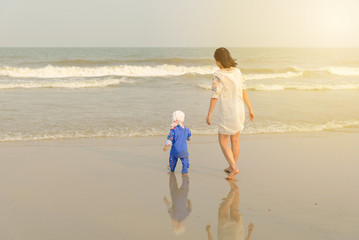 Back view of mother and son walking on the beach. beach travel at summer time concept